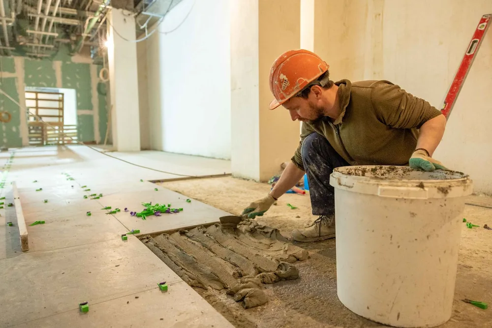 Worker laying floor tiles during a renovation
